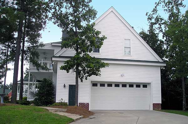 House plan exterior of a two-story home with vinyl siding, a large garage door, a second-story balcony, and prominent gables.