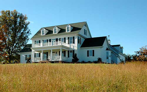 House plan exterior of a three-story Modern Farmhouse with a wrap-around porch, multiple gables, and dormer windows.