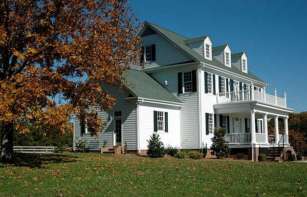 Exterior view of a two-story traditional house plan with a wrap-around porch, multiple gables, and dormer windows.