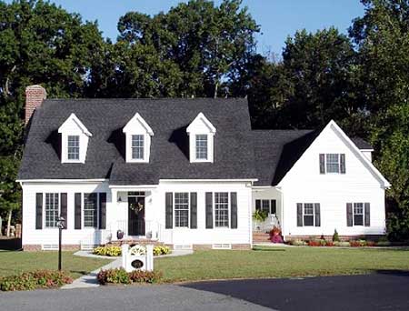 House plan exterior: White two-story home with a black roof, three gables with dormer windows, and a covered front entry.
