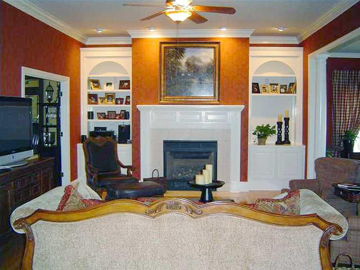 Living room interior with fireplace, built-in shelving, television, and ornate sofa.