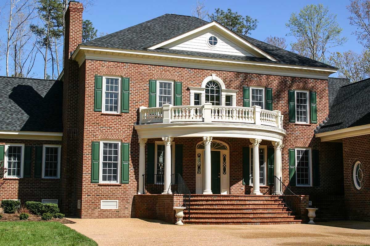 Two-story brick house plan exterior with a prominent curved portico, classical columns, second-story balcony, and symmetrical fenestration.