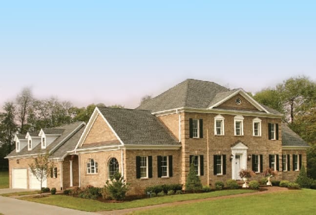 House plan exterior: Two-story brick home with a side-entry garage, multiple gables, dormers, and a covered front entrance.