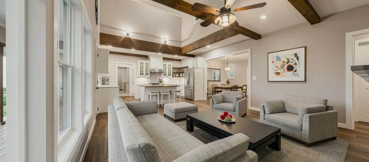 Open concept kitchen and great room with vaulted ceiling, exposed beams, fireplace, and island.