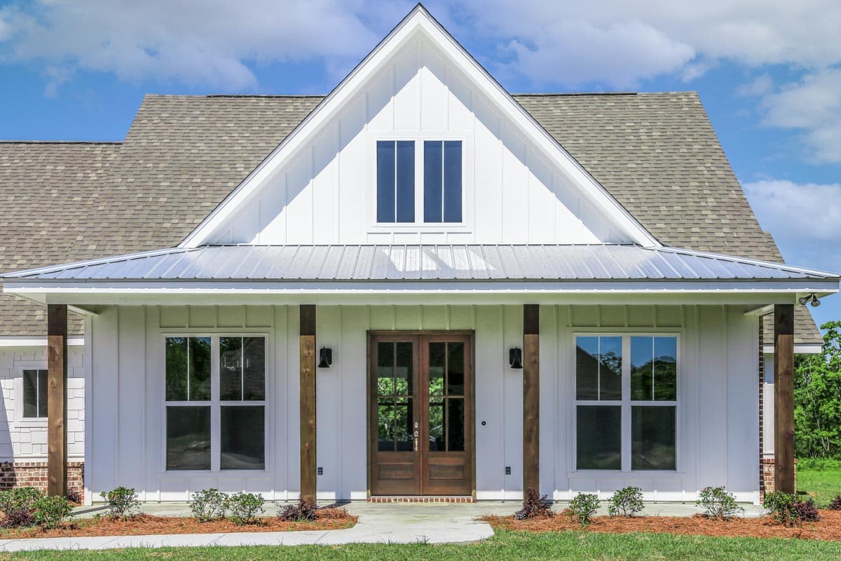 House plan exterior: Modern Farmhouse style, two stories, covered porch with wood beams, gabled dormer with double windows.