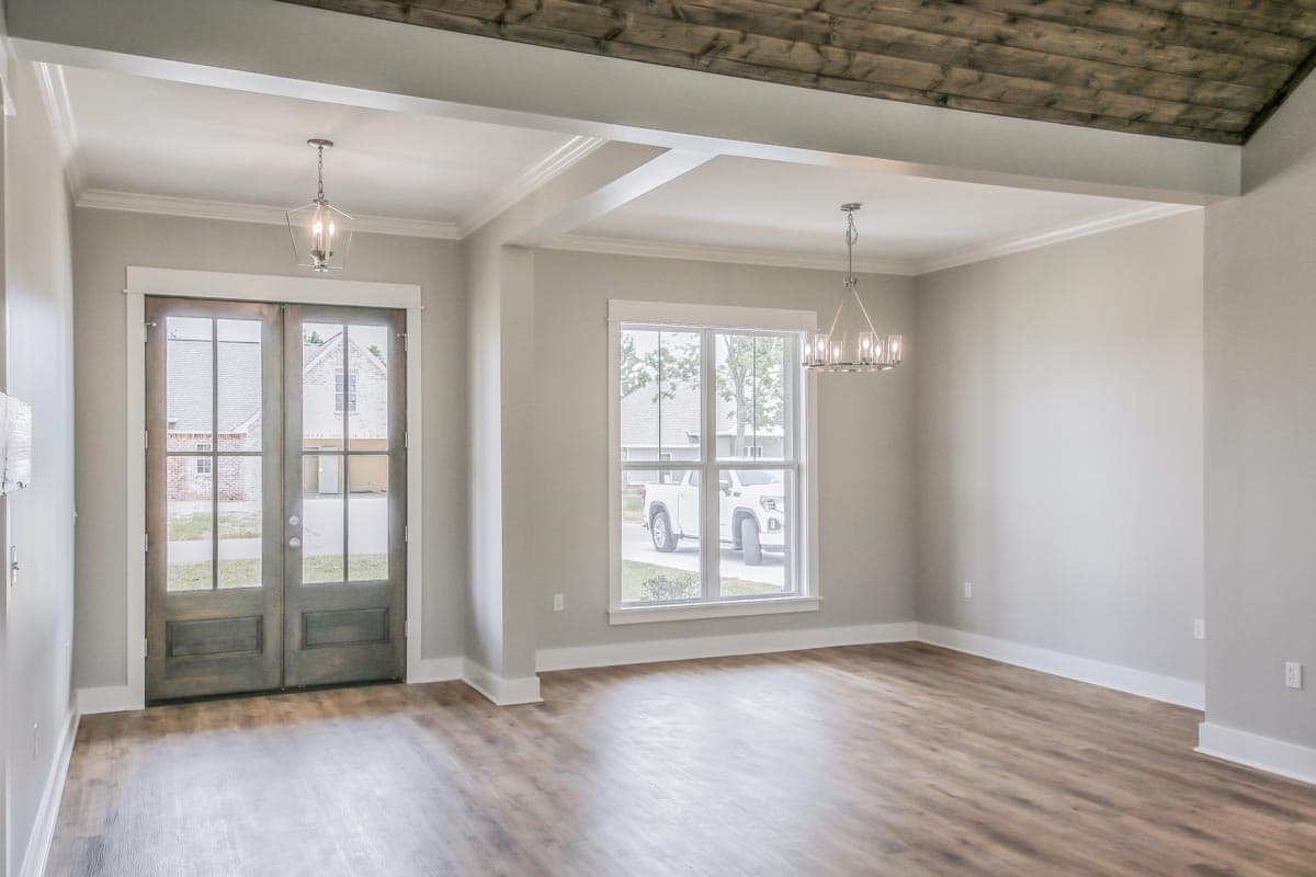Interior view showing a room with double glass doors, a large window, coffered ceiling, and wood plank ceiling detail.