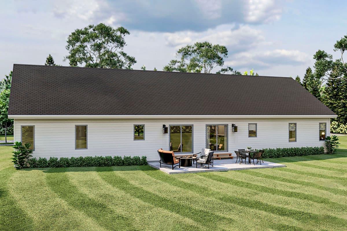 Ranch-style house plan exterior with a dark hip roof, white siding, patio with furniture, and multiple windows.