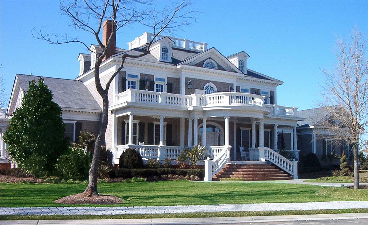 House plan exterior: two-story Colonial Revival with wraparound porch, multiple gables, dormers, and a balustraded upper deck.