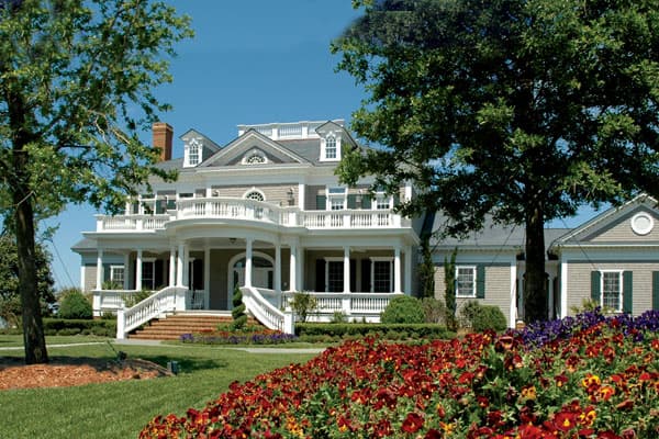 House plan exterior of a large two-story home with a wraparound porch, gables, dormers, and a prominent central entrance.