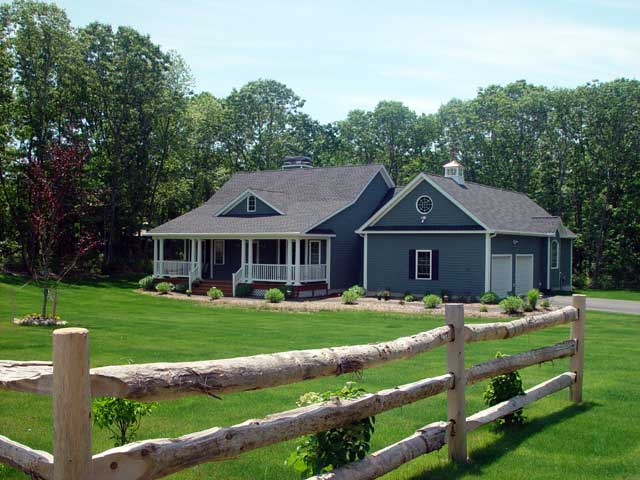 House plan exterior: One-story home with wrap-around porch, dormer, and attached two-car garage with cupola.