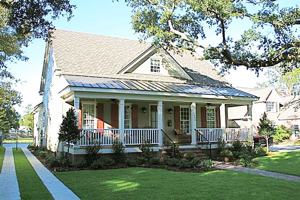 House plan exterior: Two-story home with gabled dormer, wrap-around porch with white railings, and multiple chimneys.
