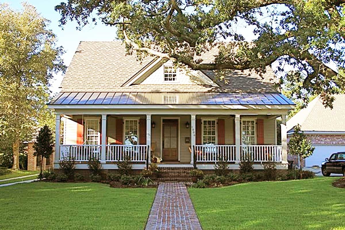 House plan exterior: Two-story home with gabled dormer, metal roof, and full-width porch with white railings.