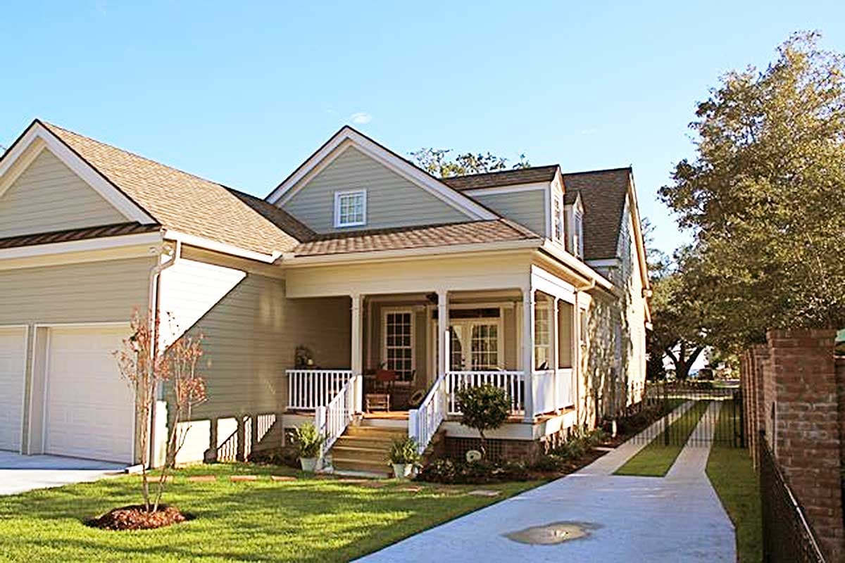 House plan exterior: Two-story home with a covered porch, dormers, and a side-entry garage.