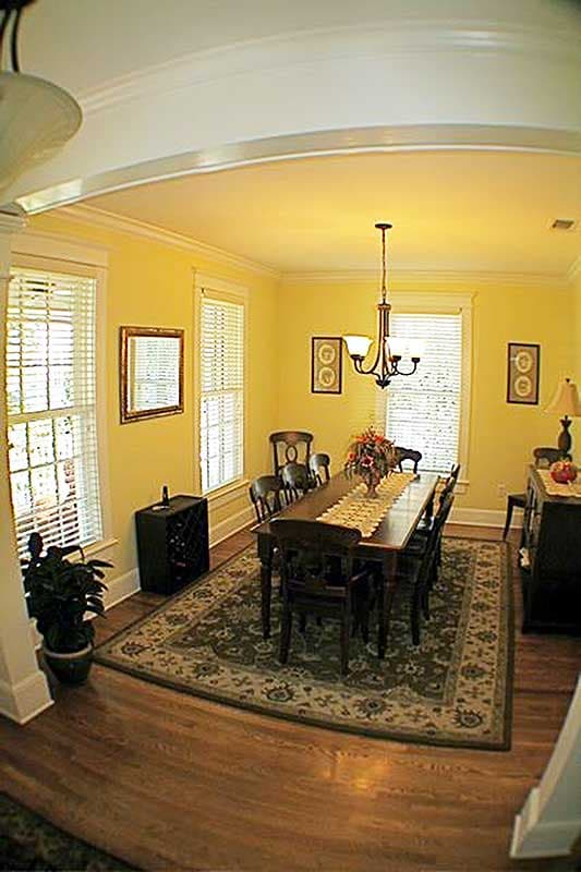 Dining room with a dark wood table and chairs, chandelier, windows with blinds, and a patterned rug.