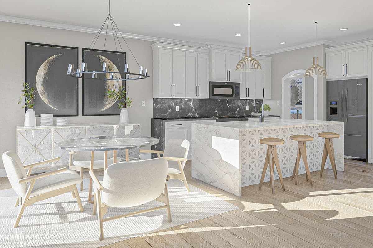 Modern kitchen with white cabinets, marble island, dining area, and stainless steel refrigerator.