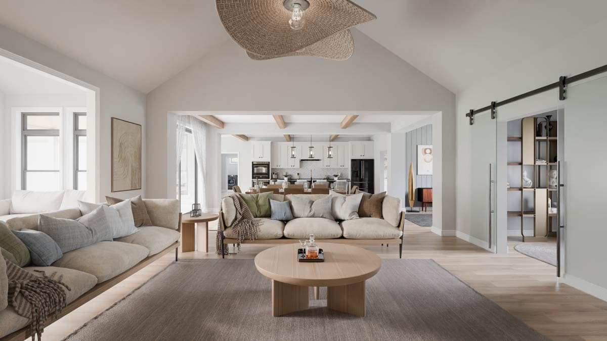 Interior view of a living room with vaulted ceiling, exposed beams, and an open view to the kitchen.