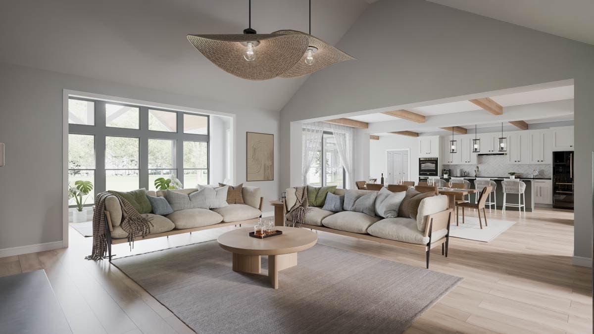 Living area with vaulted ceiling, large windows, and adjacent kitchen with island and bar seating.