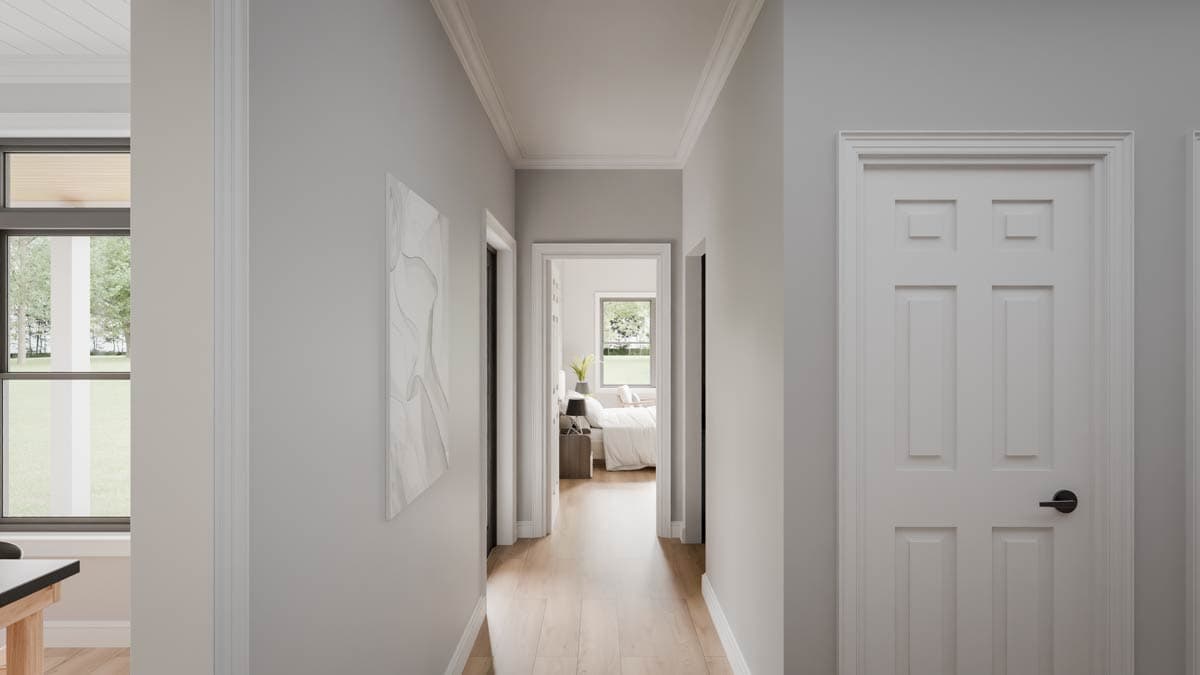 Interior hallway with light wood floors, leading to a bedroom. Features paneled doors and crown molding.