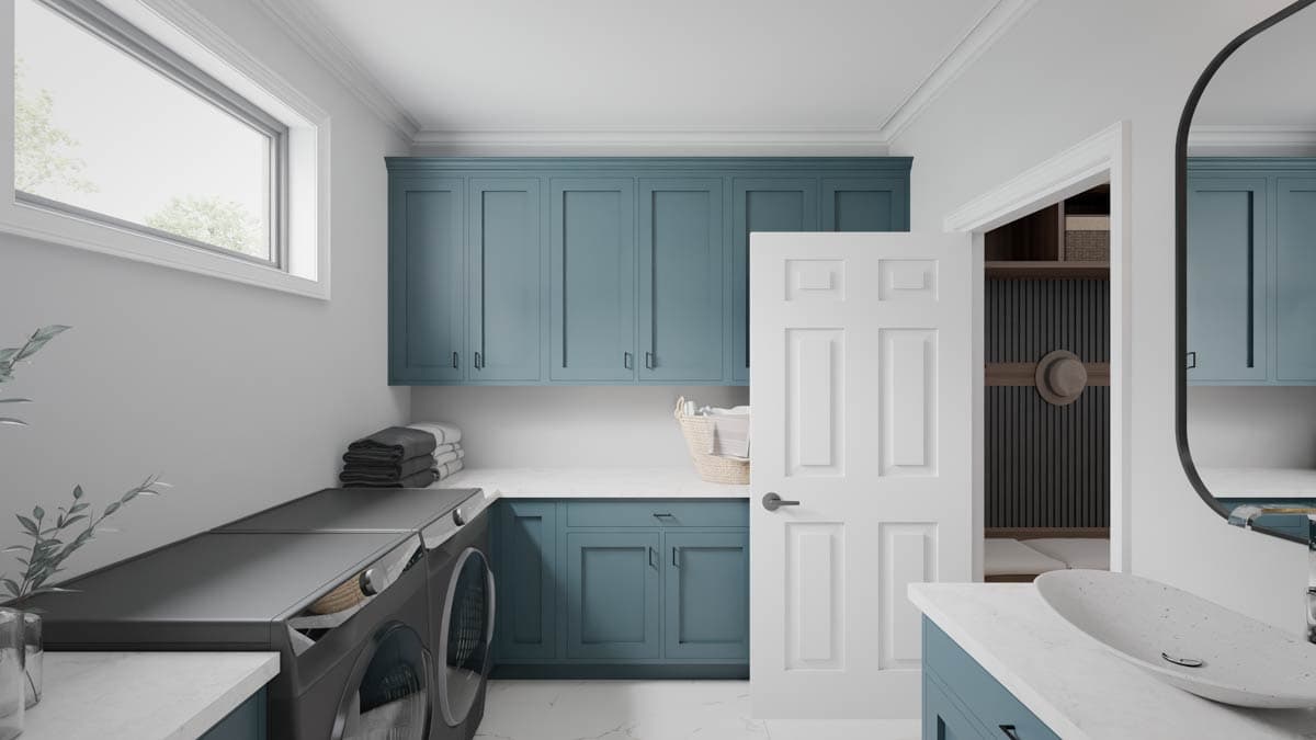 Laundry room interior with blue cabinets, washer and dryer, white countertop, and a wide window.