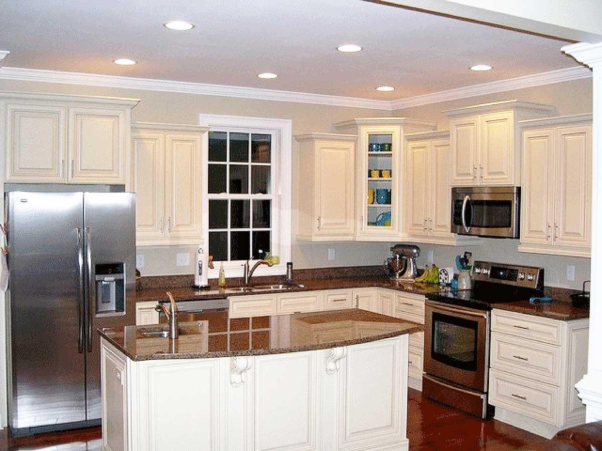 Kitchen with cream cabinets, granite countertops, stainless steel refrigerator, oven, microwave, and a central island.
