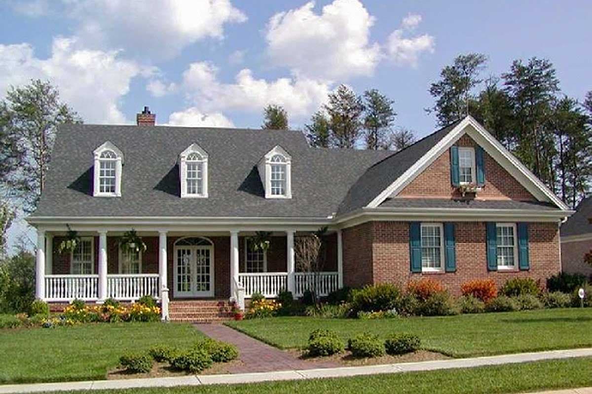 House plan exterior: Traditional brick home with a wraparound porch, dormers, and symmetrical gables.