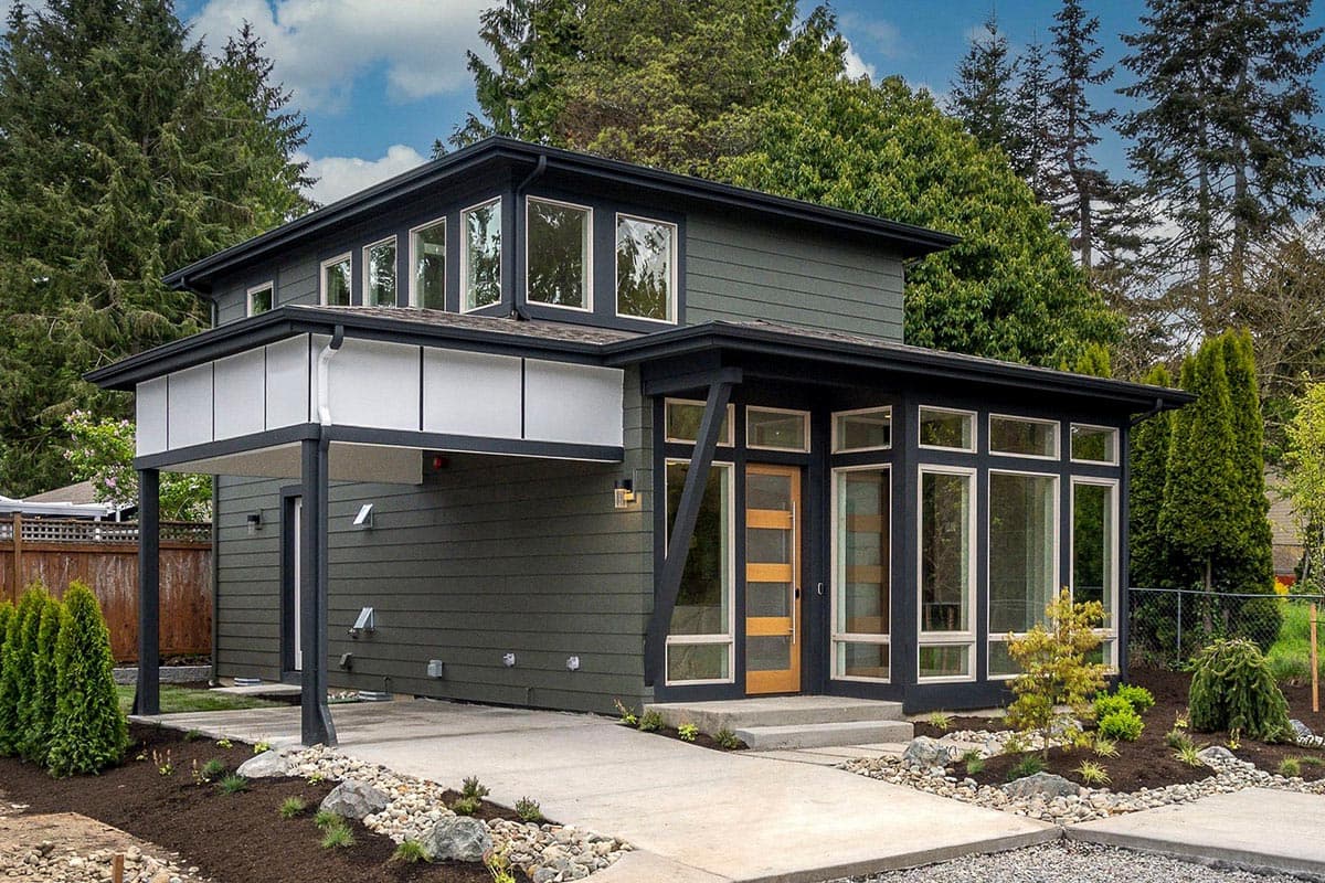 House plan exterior. Two-story modern style with flat roof and covered entry. Features include large windows and a carport with integrated beams.