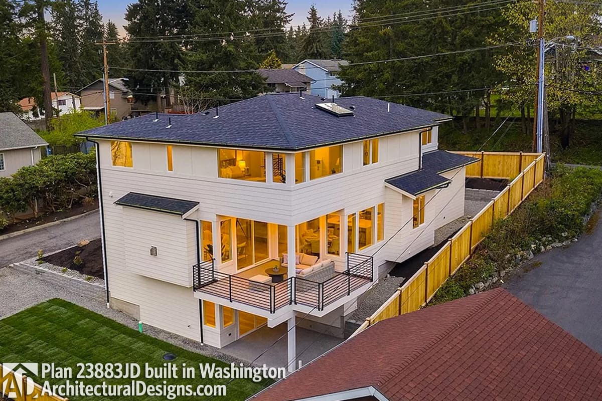 Modern two-story house plan exterior with white siding, large windows, and a wrap-around deck.