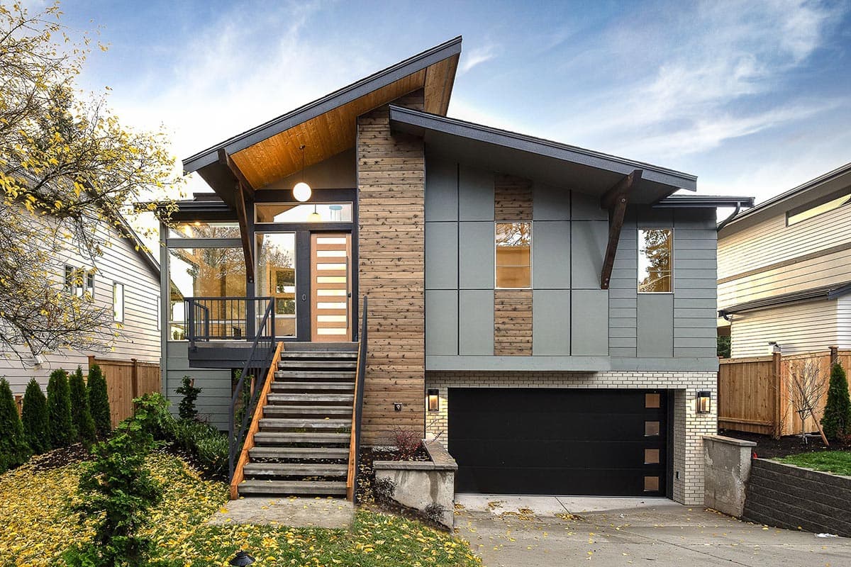 House plan exterior with two stories. Modern style with asymmetrical roofline, wood accents, and a front-facing garage with a black door.
