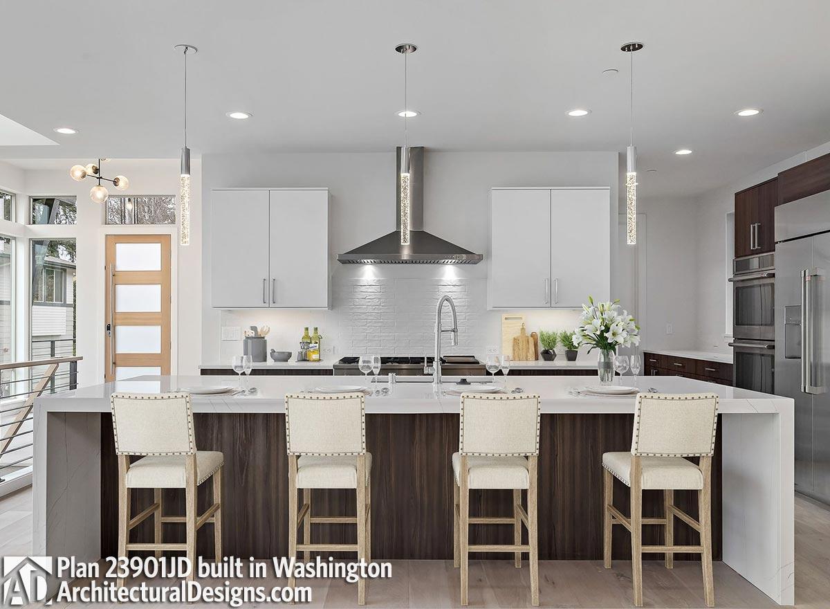 Modern kitchen with island, contemporary cabinetry, stainless steel range hood, and bar seating.