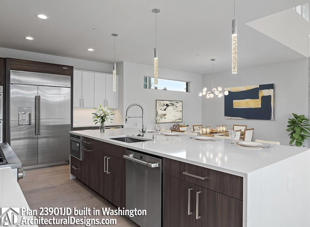 Modern kitchen with large island, stainless steel appliances, and pendant lighting. Open to dining area with contemporary chandelier.