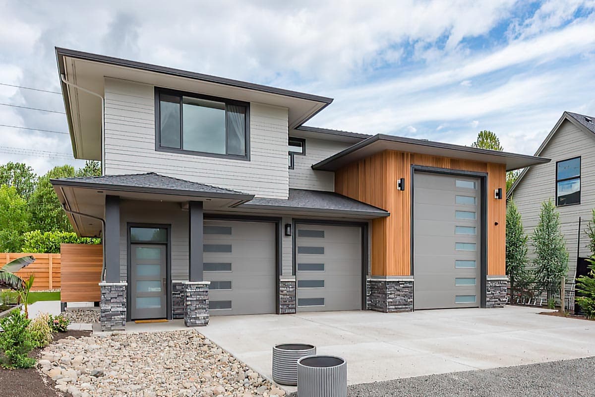 Modern two-story house plan exterior with a three-car garage, large windows, and a mix of siding and wood paneling.
