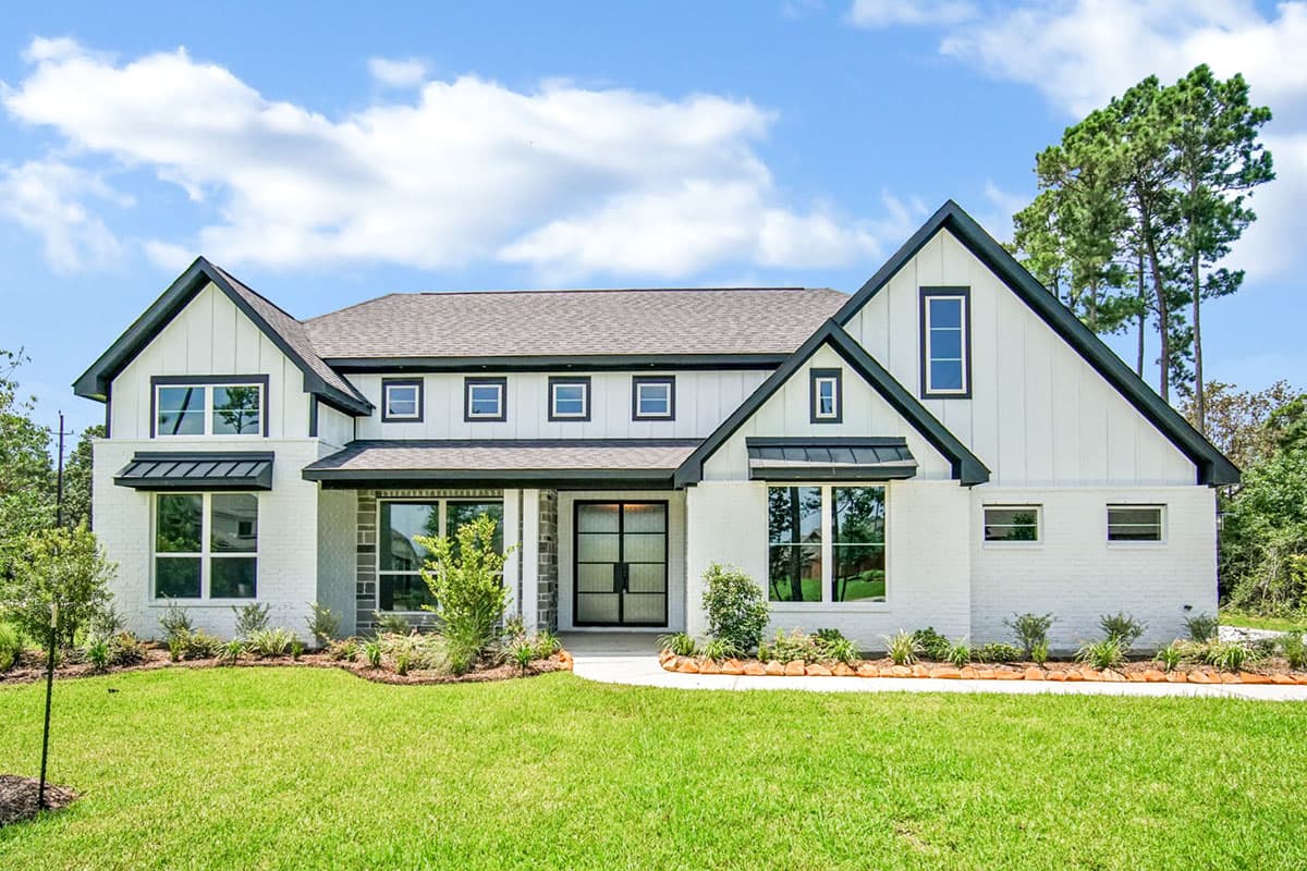 House plan exterior. Modern Farmhouse style with two stories, gabled rooflines, and a covered entry. Features include dark trim and brick accents.