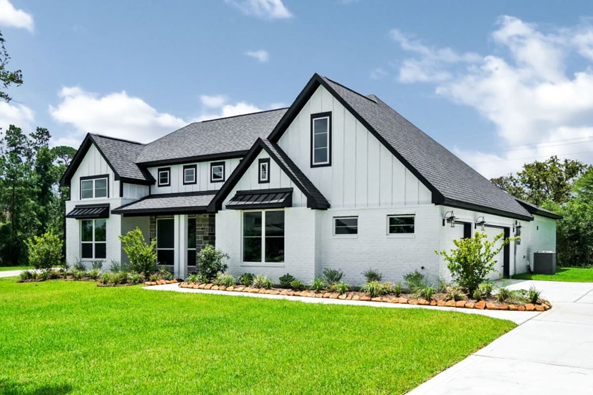 Modern Farmhouse house plan exterior with white brick, board and batten siding, metal awnings, and a two-car side-entry garage.