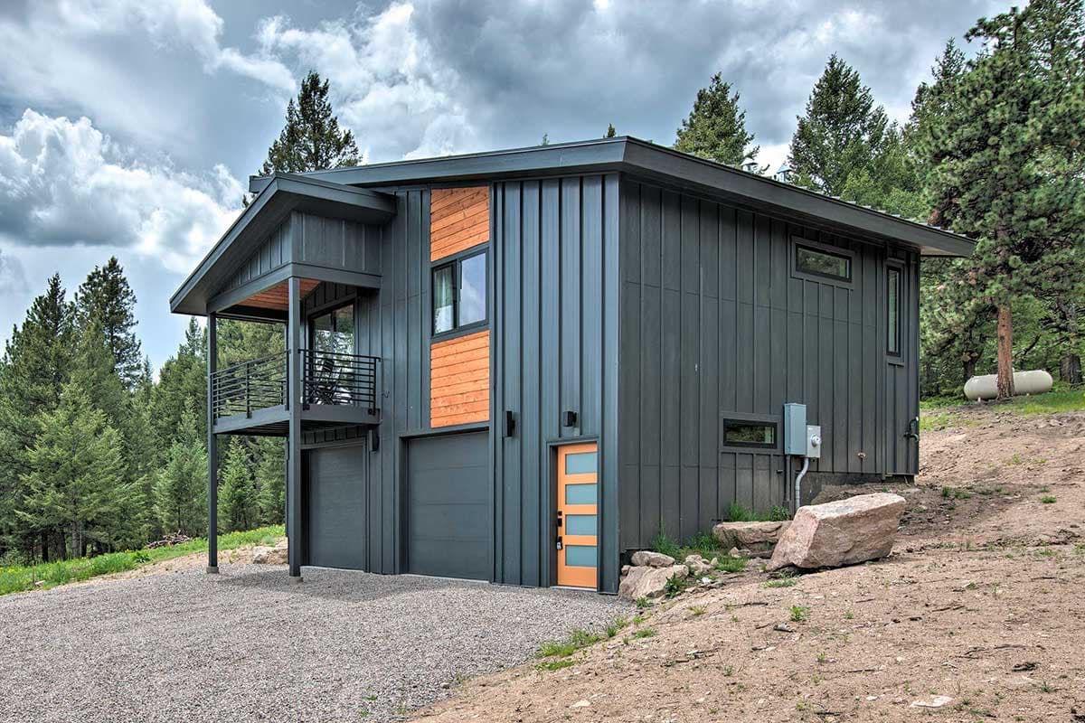 Modern house plan exterior with standing seam metal siding, balcony, two garage doors, and wood accents.
