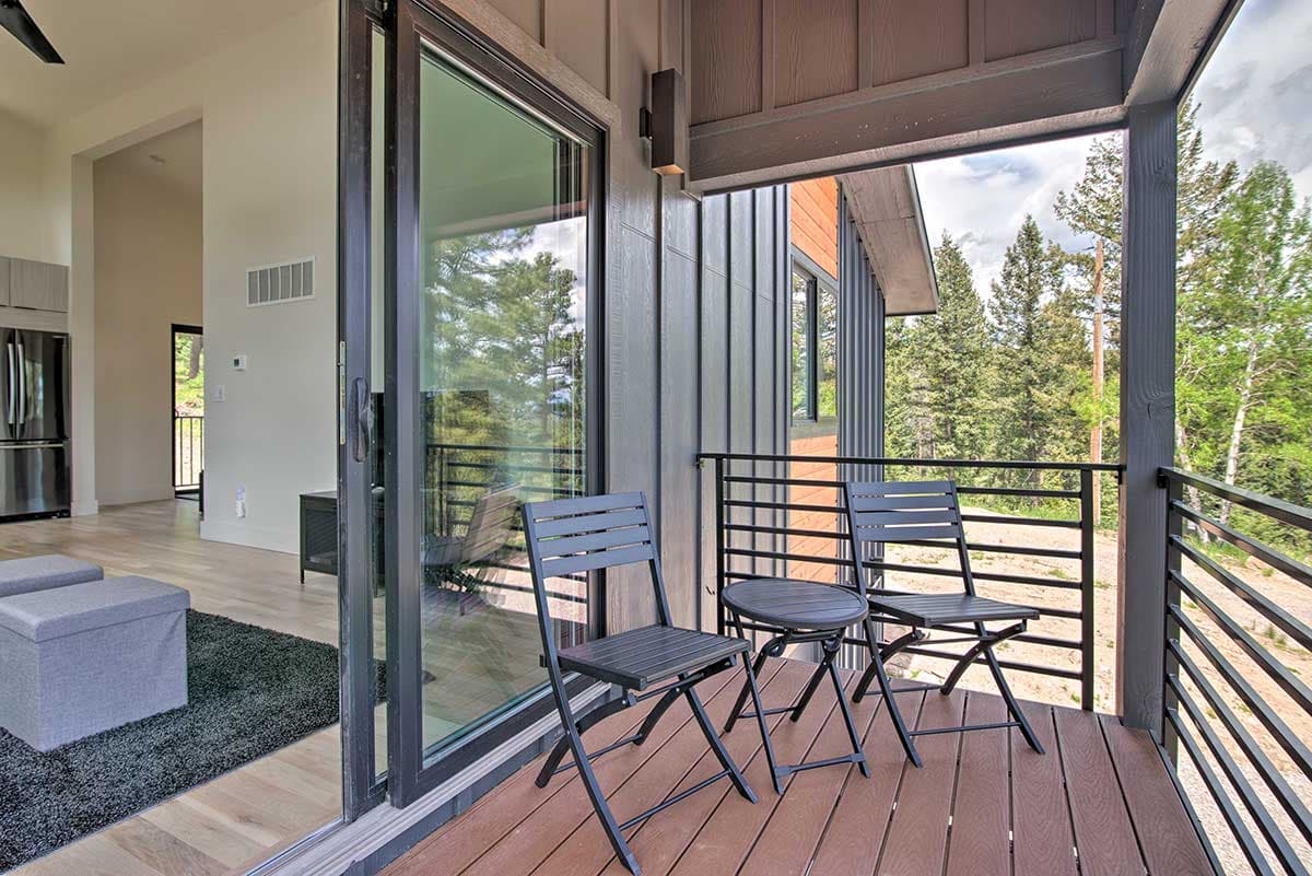 Modern house exterior with vertical siding, large sliding glass doors, and a covered deck with seating.