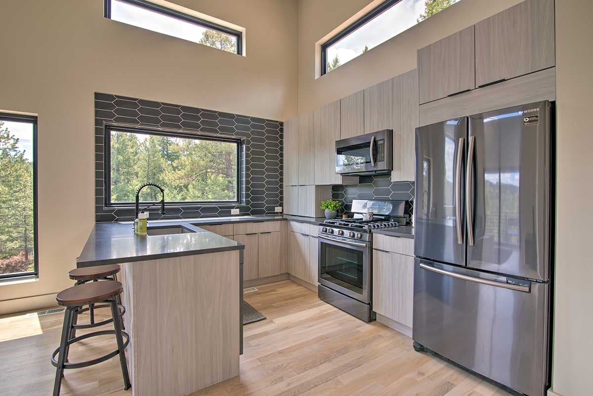 Kitchen with modern cabinets, large window, gas range, and stainless steel refrigerator.