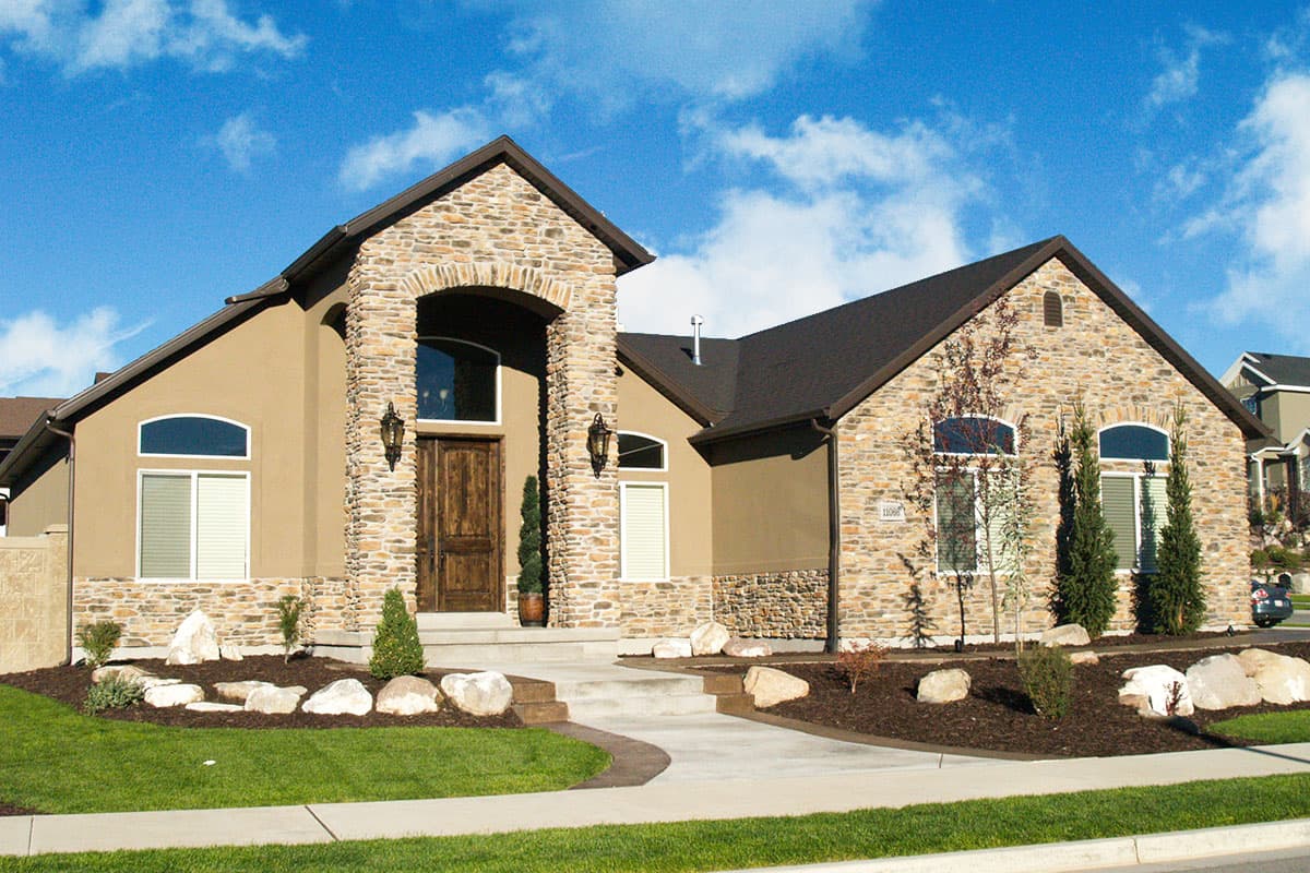 Ranch house plan exterior with stone accents, arched entry, and multiple gables.