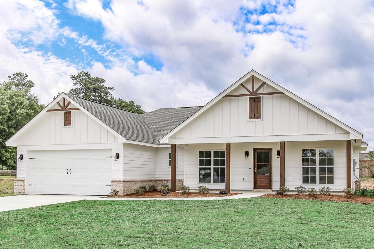 House plan exterior. Modern Farmhouse style, single story. Features include a front porch, gables with decorative brackets, and a two-car garage.