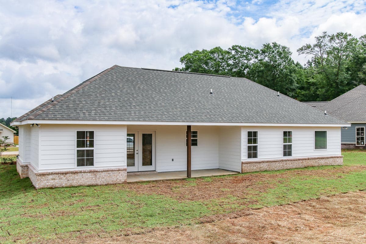 House plan exterior: One-story, white horizontal siding, covered patio with wood post, and brick foundation.