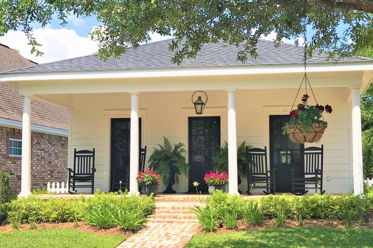 House plan exterior featuring a covered porch with columns, three dark doors, and rocking chairs.