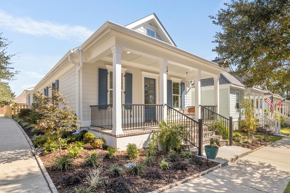 House plan exterior. Two-story home with Craftsman style. Features include a front porch with columns, blue shutters, and a gable roof.