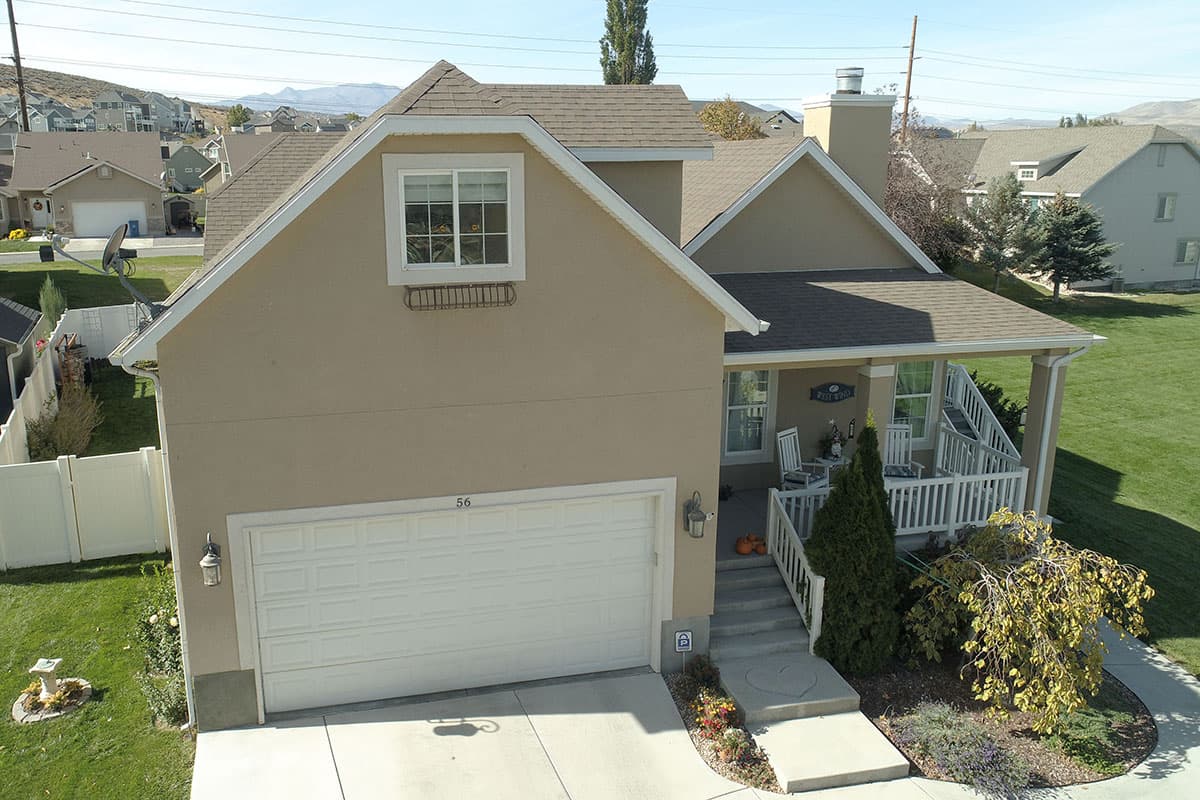 House plan exterior: Two-story home with front-facing garage, covered porch with white railings, and prominent gable.