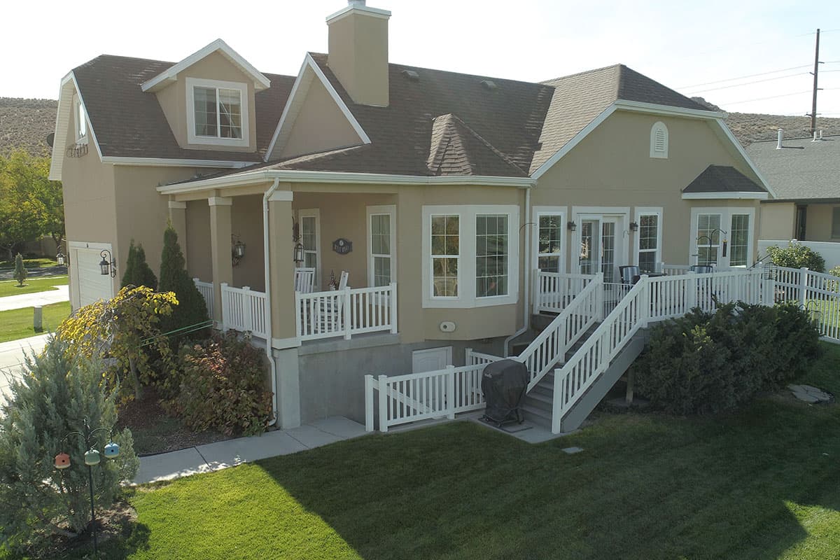 House plan exterior: Two-story home with a covered porch, gables, dormers, and a side-facing garage.