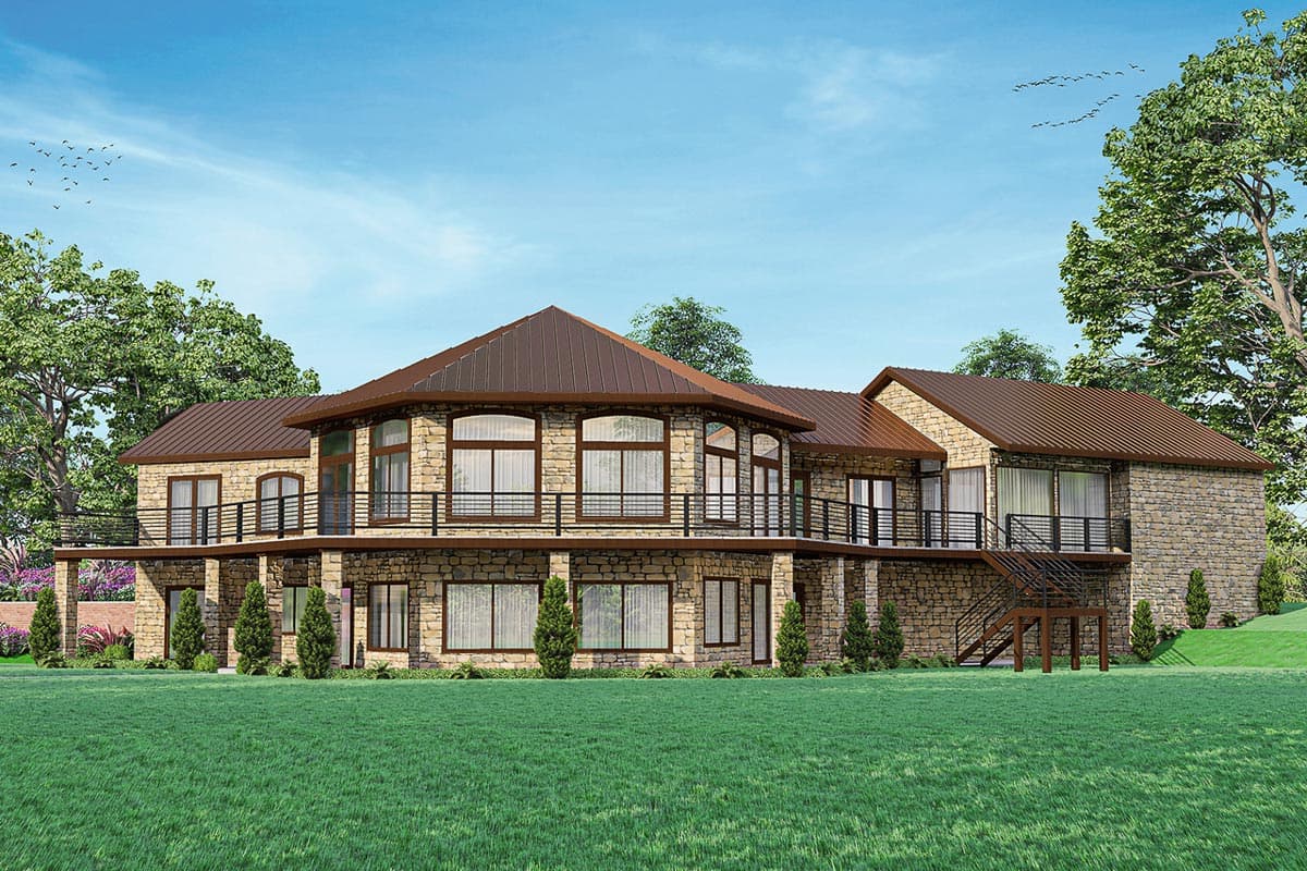 House plan exterior with two stories. Stone facade, metal roof, wrap-around balcony with black railing, and multi-paned windows.