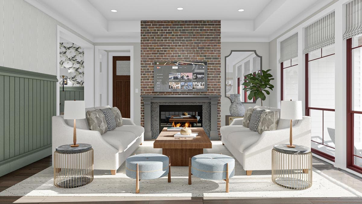 Living room with brick fireplace, two sofas, wood coffee table, and large windows. Beadboard wainscoting visible.