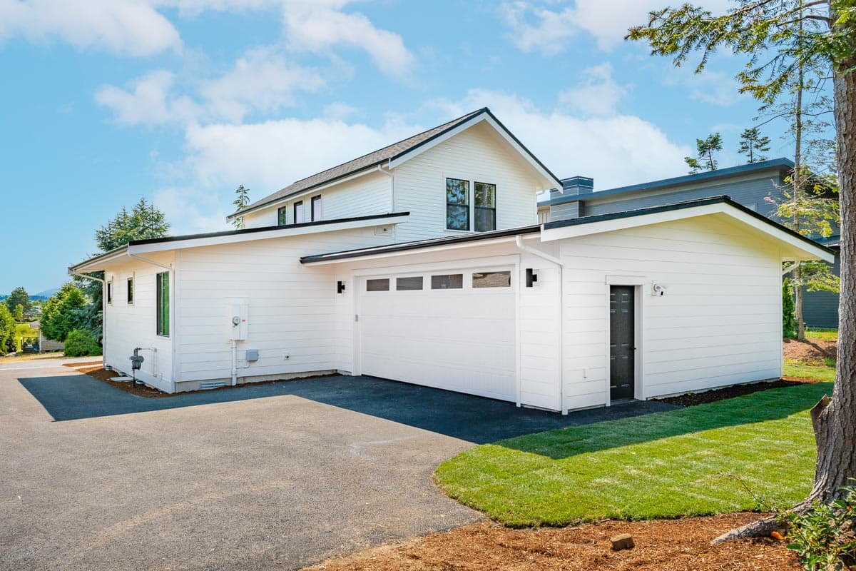 Modern house plan exterior with white siding, a two-car garage, and a prominent gable roofline.