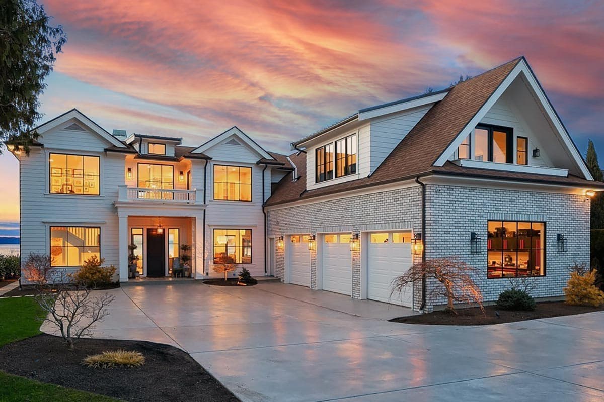 House plan exterior. Two-story Modern Farmhouse with gables, multiple dormers, and a three-car garage. Features a balcony and brick accents.