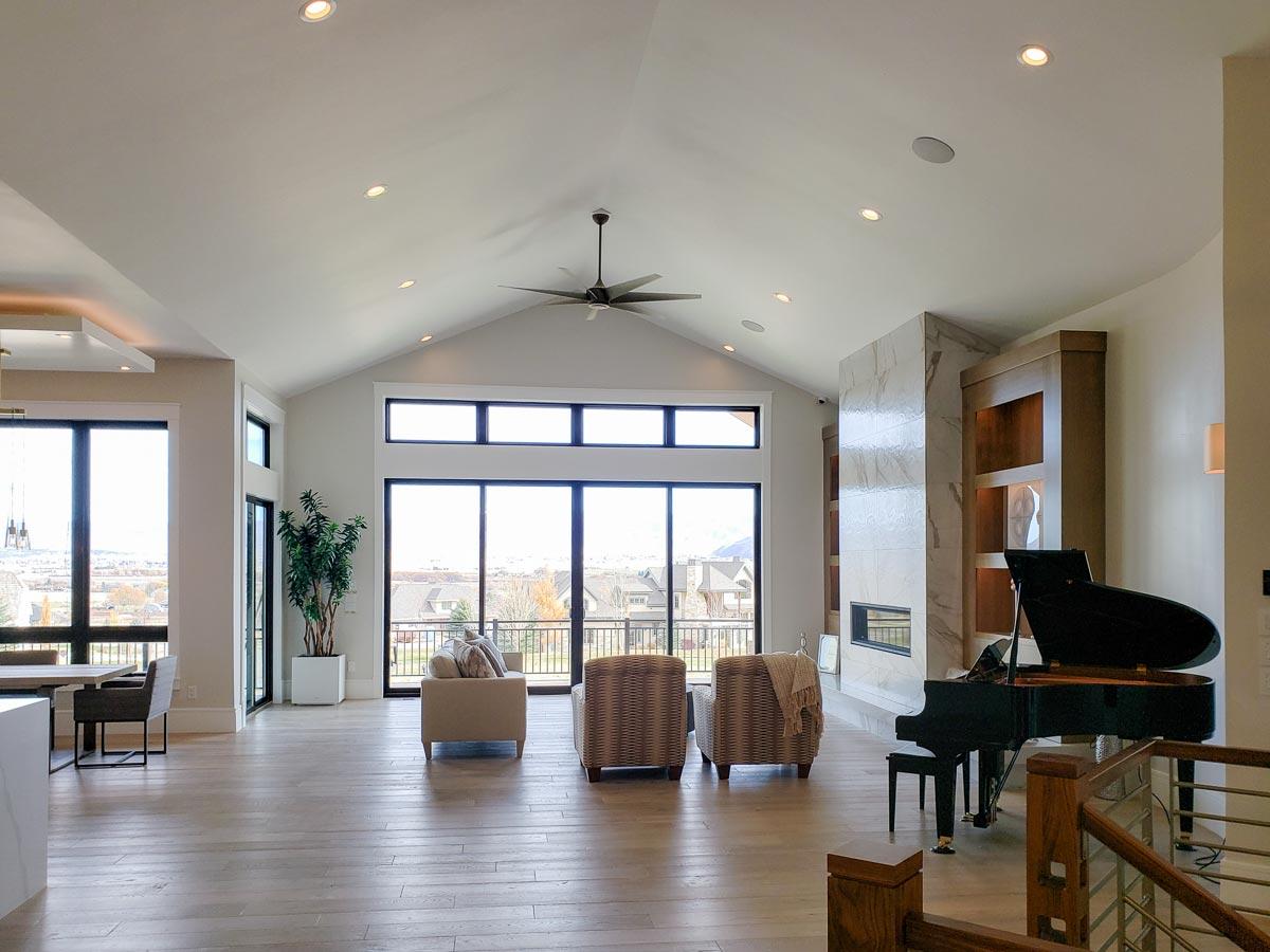 Great room with vaulted ceiling, large windows, fireplace, grand piano, and seating area.