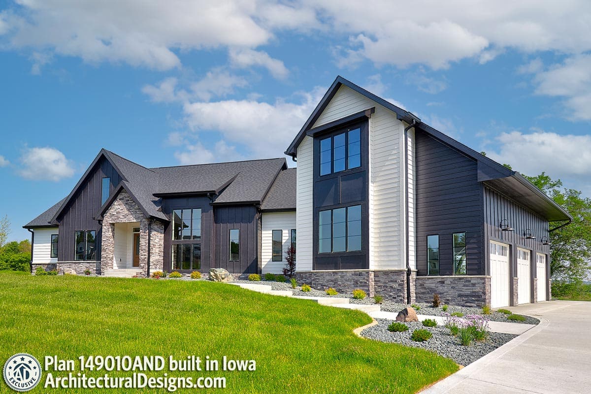 Modern Farmhouse house plan exterior with stone accents, dark vertical siding, white horizontal siding, and a three-car garage.