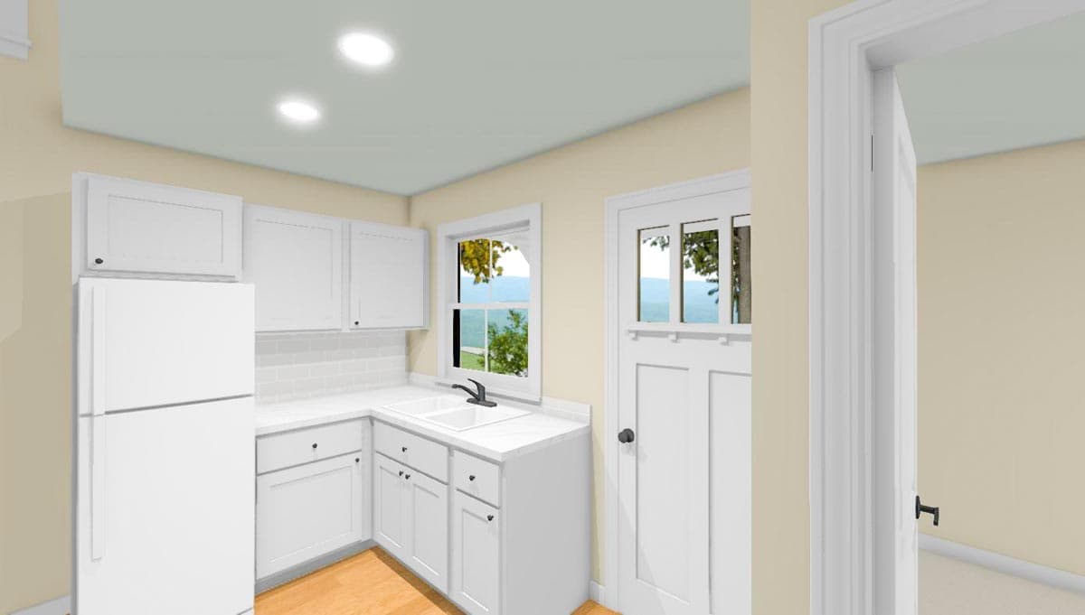 Kitchen area with white cabinets, refrigerator, sink, and door with transom windows.